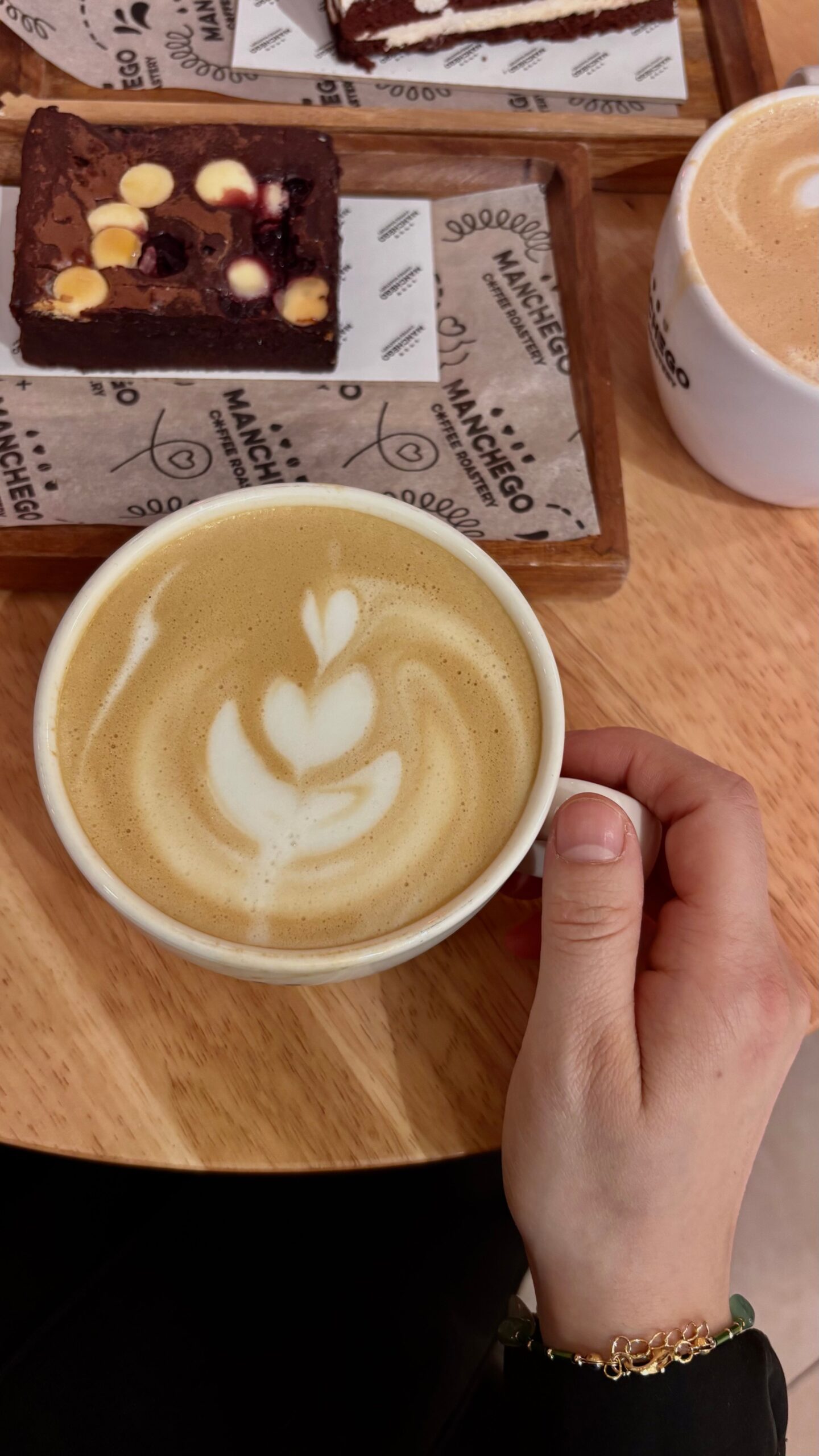 Cozy coffee break with beautifully crafted latte art and delicious brownies on a wooden table.